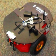 Image shows the Pioneer 3 robot we are using.  Notice the round sonar sensors along the top of the front face.